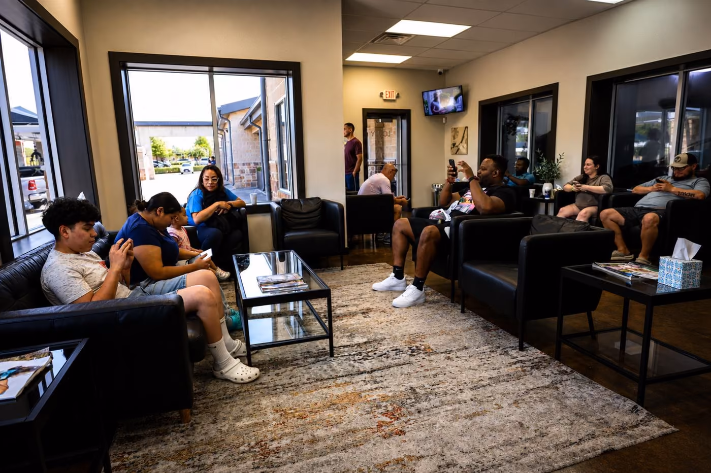 Busy customer lounge with families and customers relaxing in black leather chairs